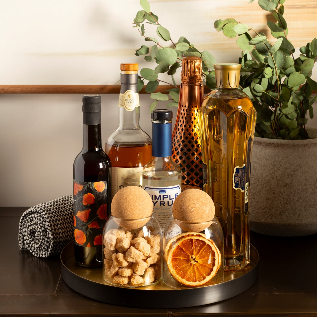 Sienna Maison Madison Cork Ball Dishwasher-Safe Borosilicate Glass Canisters Set of 4 sizes styled display on kitchen counter pantry bar with alcohol, sugar, and dried fruit slices - with Savina Rustic Tuscan Vase and Kiana Towel