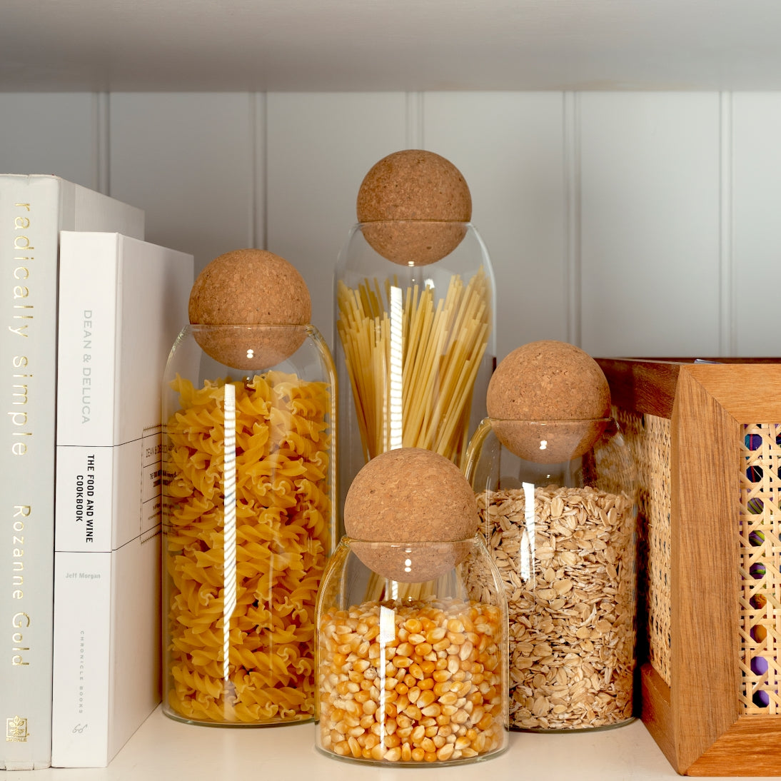 Sienna Maison Madison Cork Ball Dishwasher-Safe Borosilicate Glass Canisters Set of 4 sizes styled display on kitchen counter pantry organizing grains - of pasta, rice, and popcorn kernels with Milo Acacia Rattan Storage Bin Box