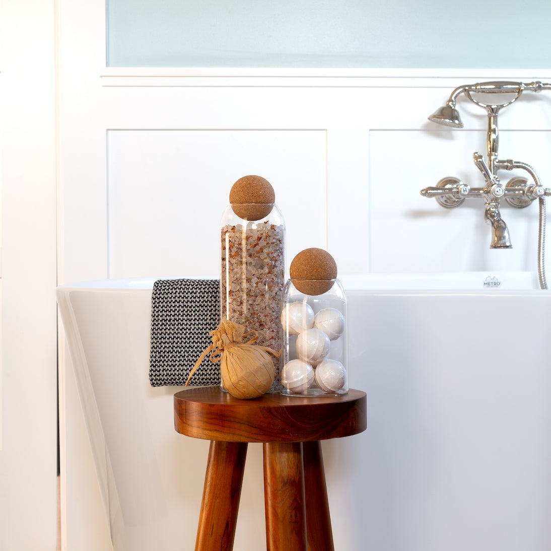 Sienna Maison Madison Cork Ball Dishwasher-Safe Borosilicate Glass Canisters Set of 4 sizes styled display on bathroom stool next to bathtub organization of bath salts and bath bombs with Kiana Towel